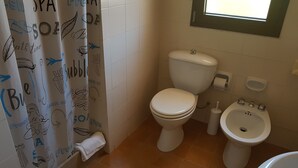 A bathroom with a toilet, bidet, and a shower curtain with various doodles. - Hotel del Molo (Palau)