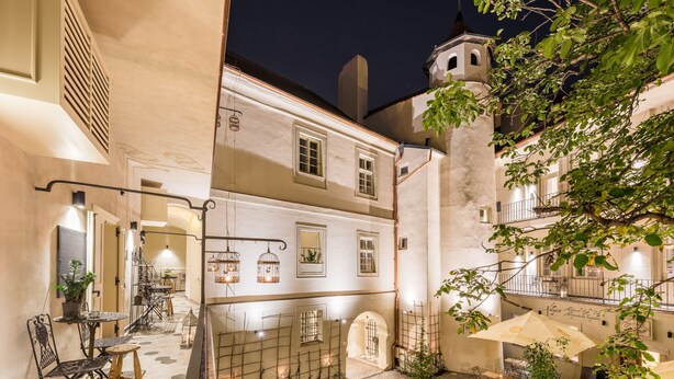 A courtyard with outdoor seating, a stone bench, and a potted plant. - MOOo by the Castle (Prague)
