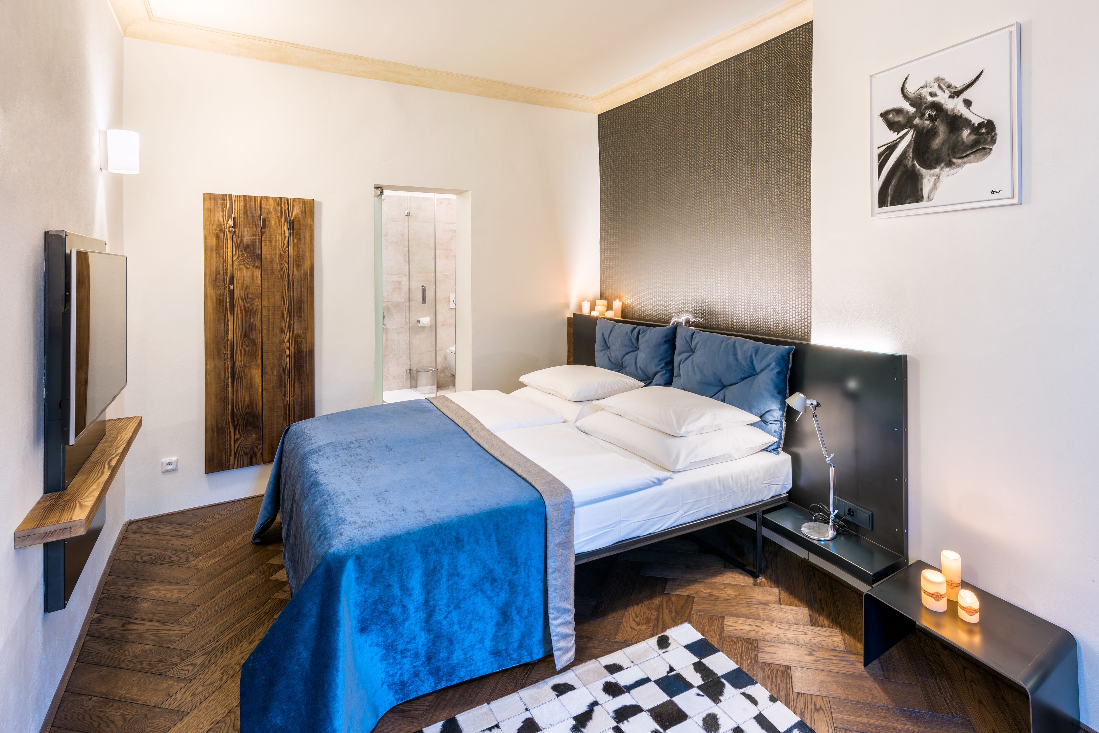 A modern bedroom with a bed, bedside tables, a TV, and a wooden wardrobe.