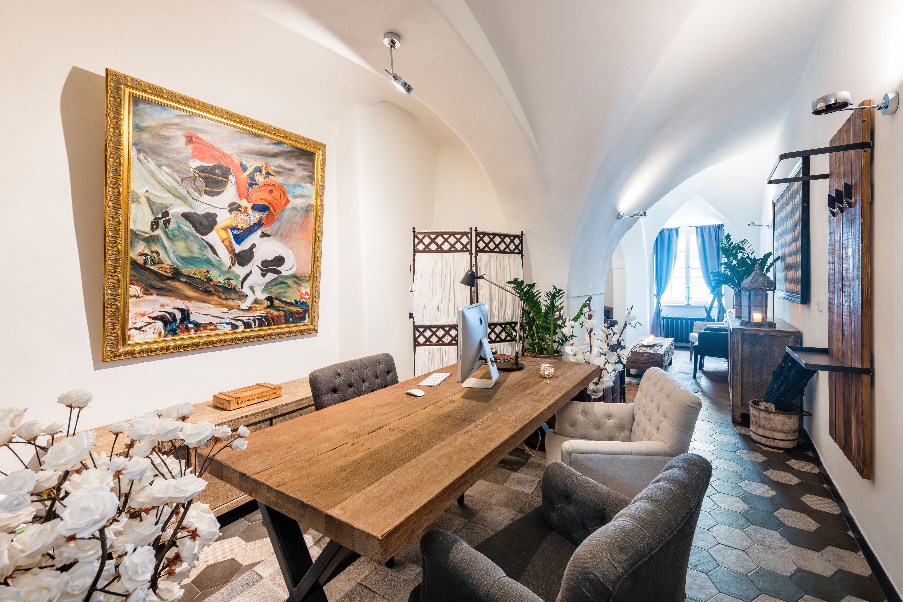 A spacious dining area with a wooden table, comfortable seating, and a large painting on the wall.