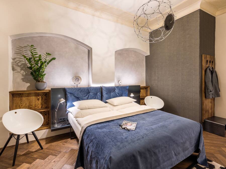 Een moderne slaapkamer met een bed, nachtkastjes, een potplant en een kapstok.