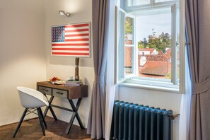 A room with a desk, a chair, a radiator, and a window with curtains.
