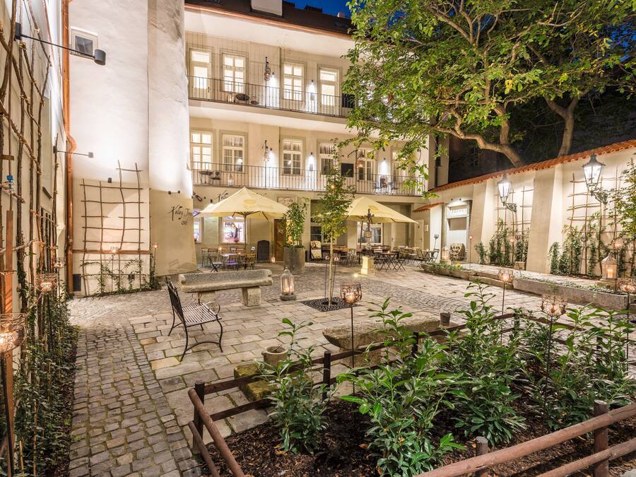 A courtyard with outdoor seating, a brick pathway, and a garden area.