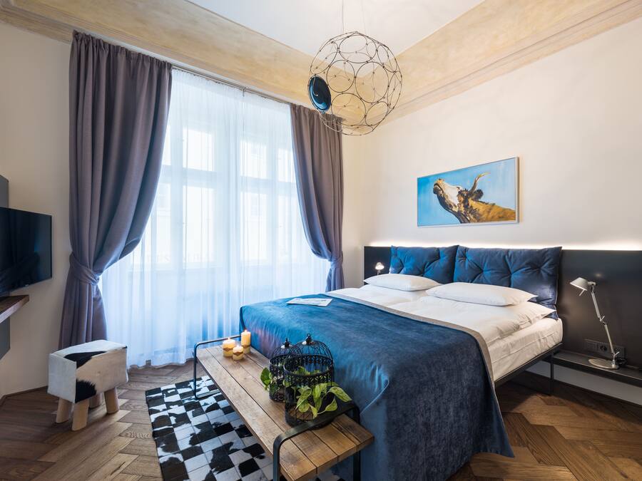 Een moderne slaapkamer met een groot bed, een televisie, een bureau en een raam met gordijnen.