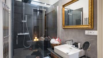 A modern bathroom with a glass-enclosed shower, a large mirror, and a vanity with a sink and towel rack.