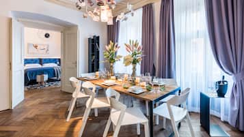 A dining area with a wooden table set for six, white chairs, and a vase of flowers.