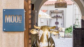 Un senyal amb la inscripció 'MOOO BY THE CASTLE' i una estàtua daurada de vaca a l'entrada.