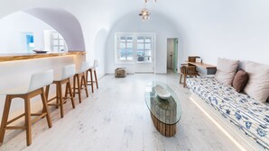 A modern interior with a bar area, seating, and a large window. - Hyperion Oia Suites (Santorini)