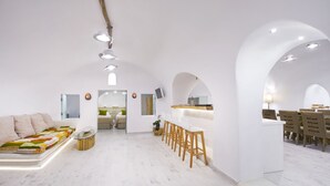 A modern, minimalist interior with a central seating area, a bar, and a dining space. - Hyperion Oia Suites (Santorini)