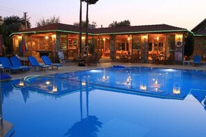 A pool area with lounge chairs and a bar area with tables and chairs. - Gorkem Hotel & Apartments (Fethiye)