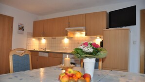 A kitchen with wooden cabinets, a tiled backsplash, a lit candle on the table, and a bouquet of flowers.