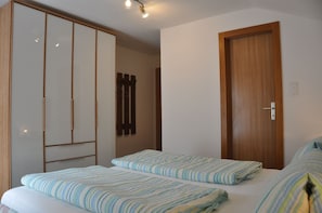 A bedroom with two beds, a wardrobe, and a wooden door.