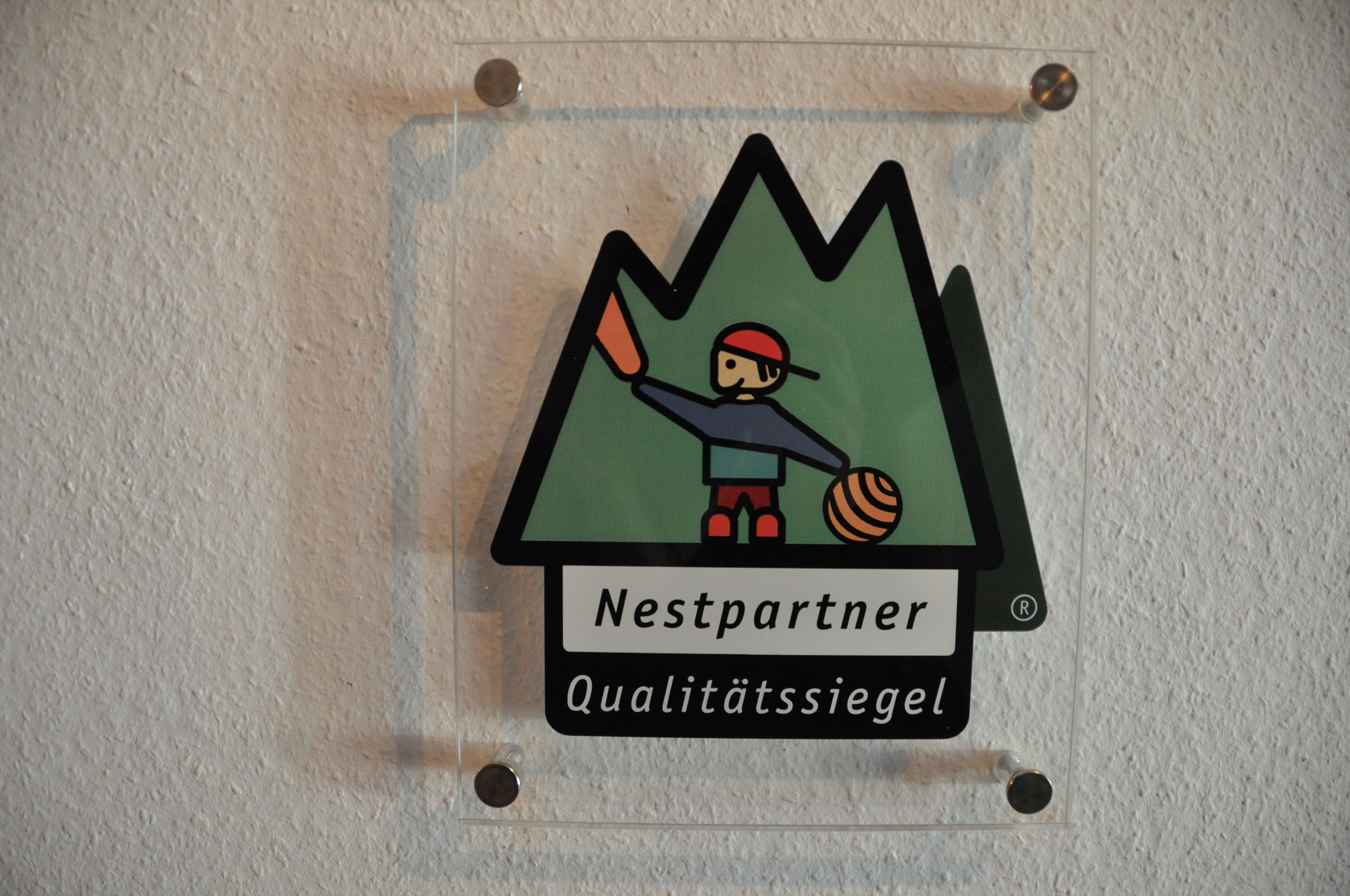 Un letrero de Nestpartner con una montaña y una figura ondeando una bandera.