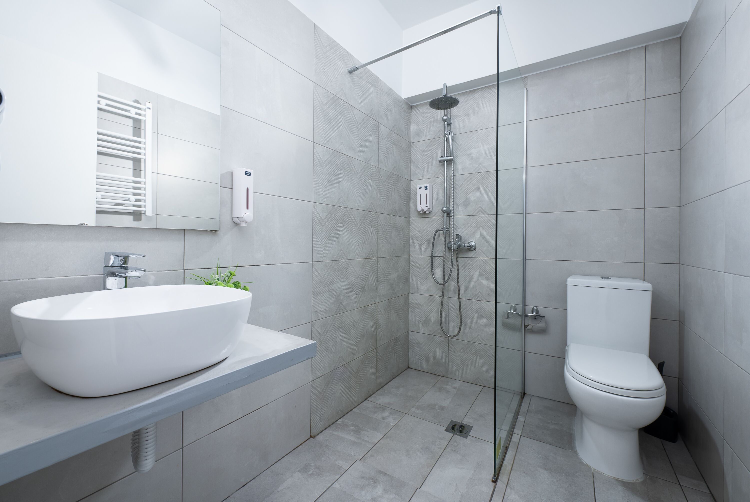 Ein modernes Badezimmer mit einem großen weißen Waschbecken, einer Toilette und einer Duschkabine.
