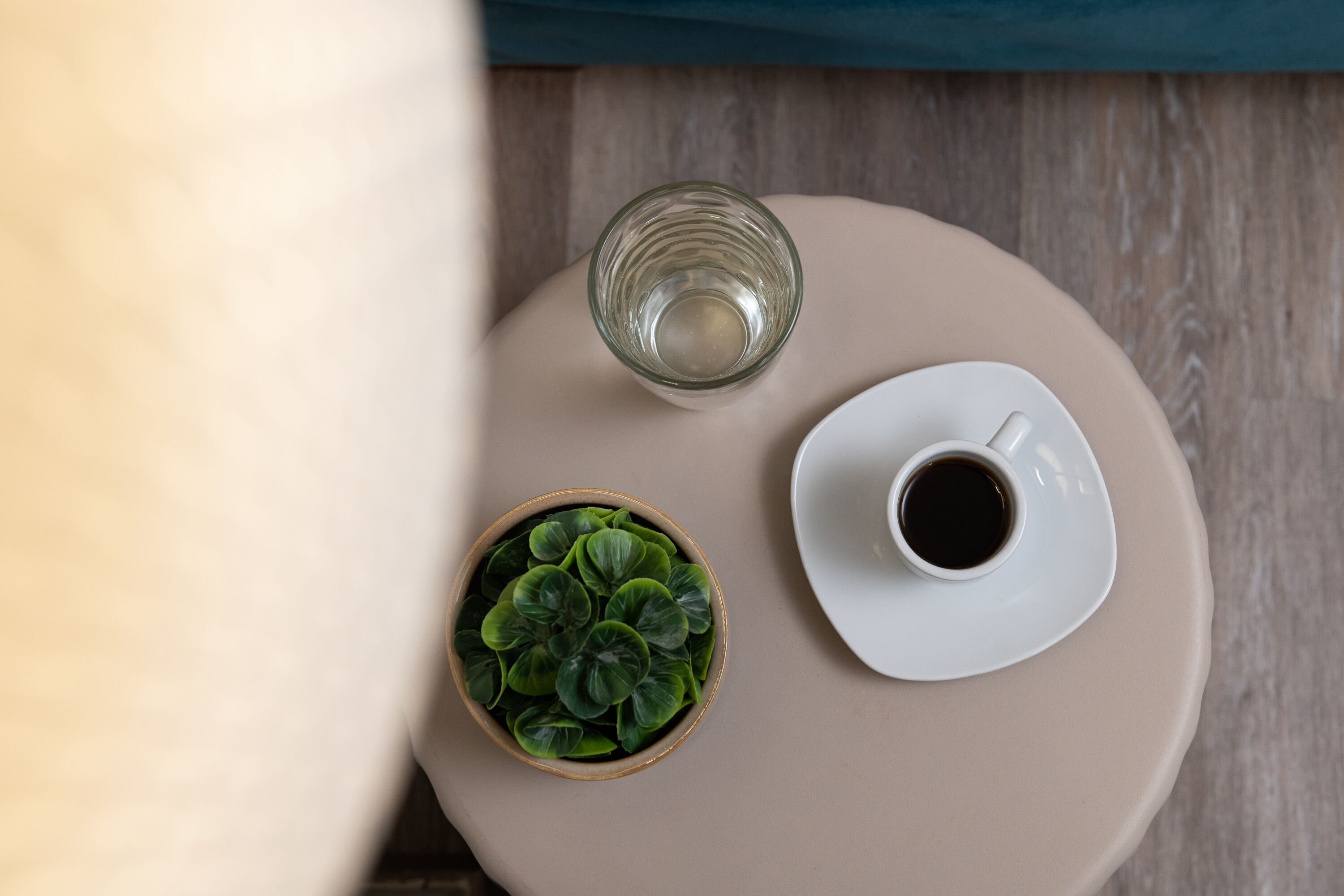 A round table with a glass, a cup of coffee, and a small plant.