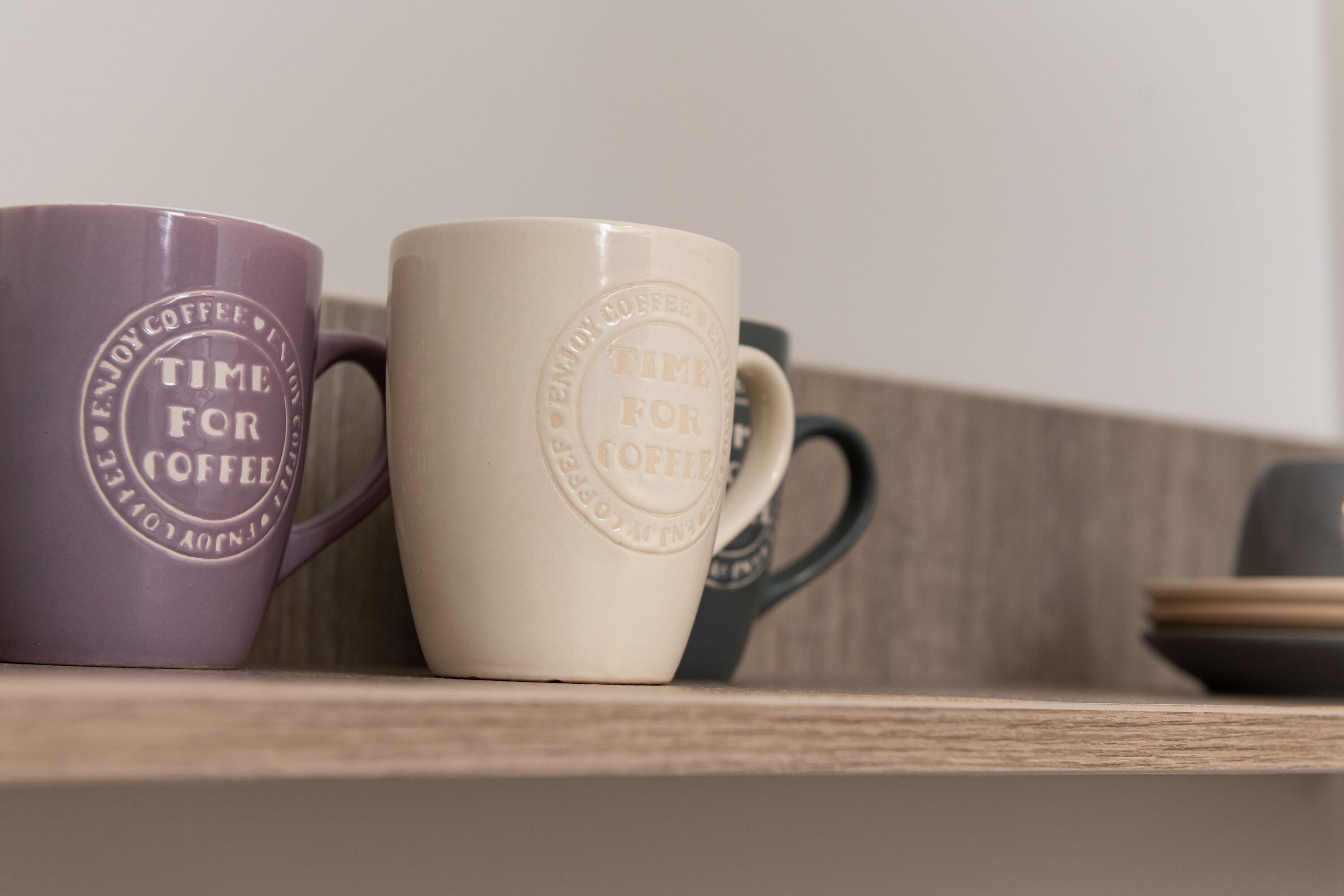 Two coffee mugs on a shelf with a wooden background.