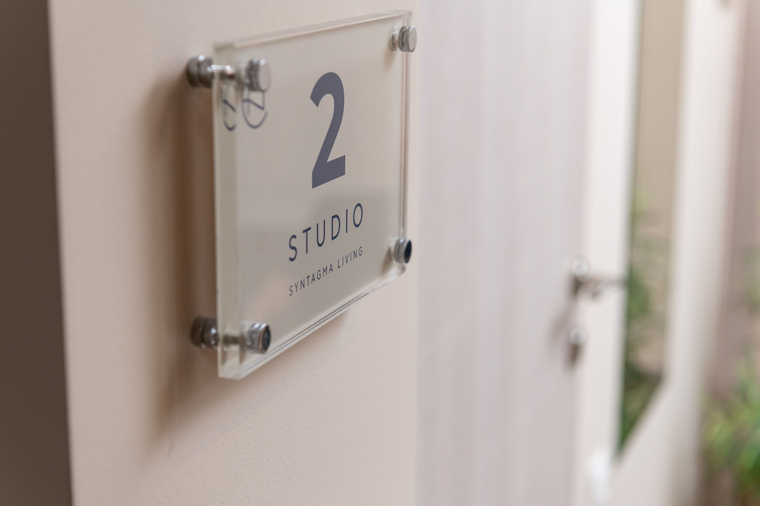 A clear sign with the number 2 and the words "STUDIO" and "SYNTAGMA LIVING" on a wall.