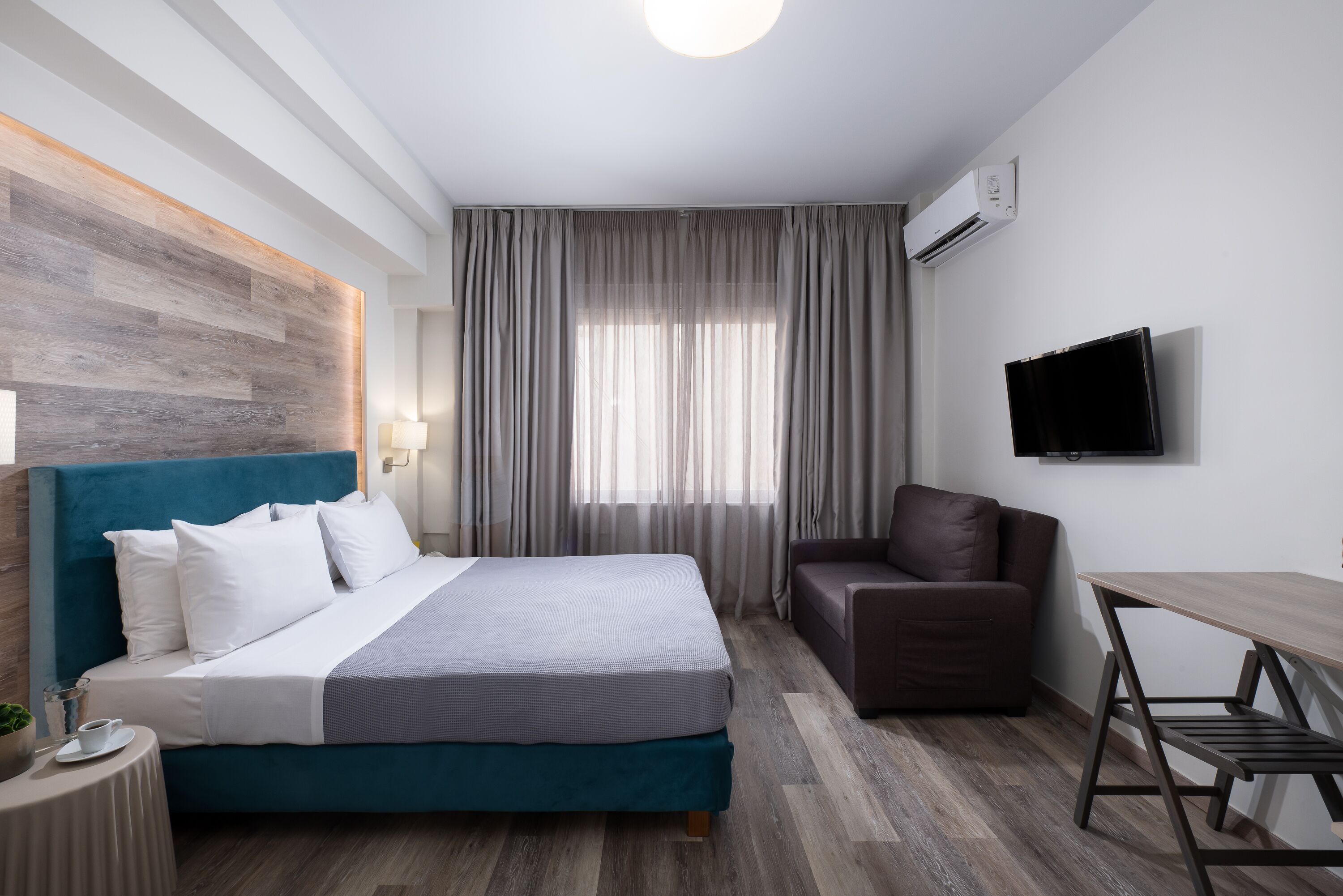 Una habitación de hotel moderna con una cama, un escritorio, una silla y un televisor.