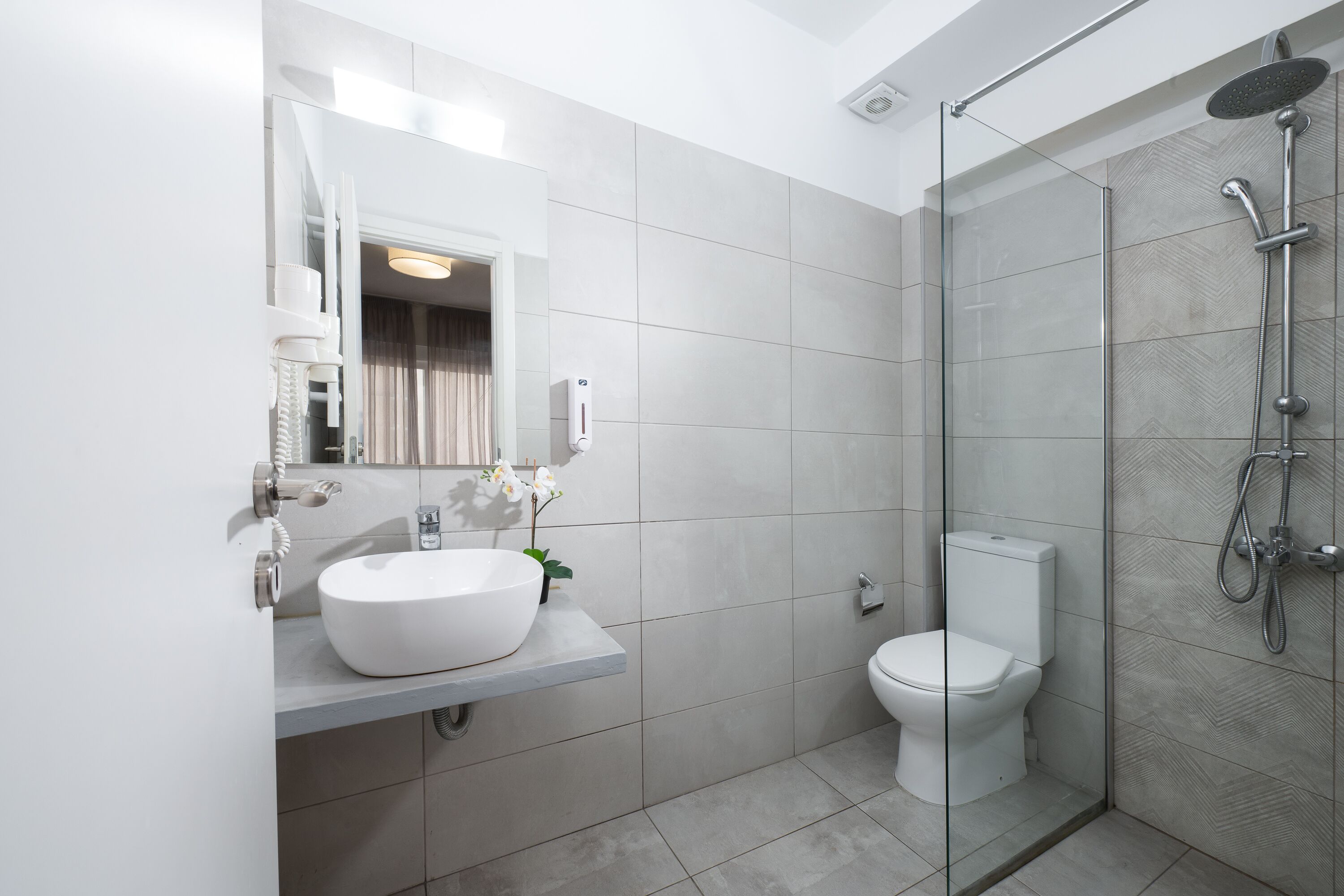 A modern bathroom with a glass shower enclosure, a white sink, and a toilet.