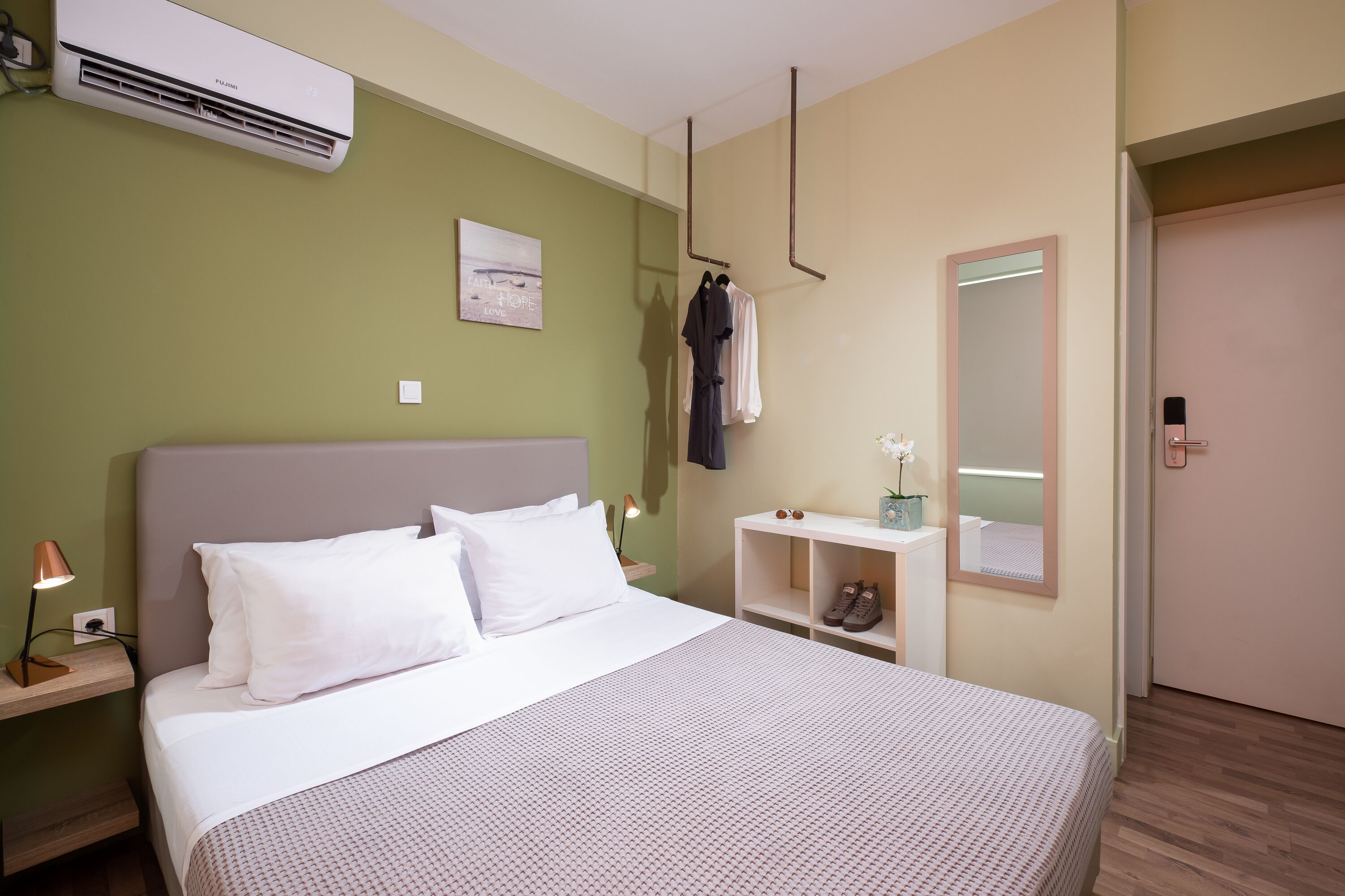A neatly arranged hotel room with a bed, bedside table, and a mirror.
