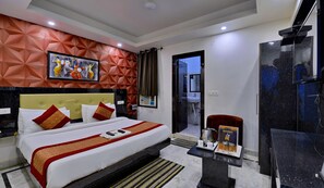 A hotel room with a bed, a desk with a coffee maker, and a view of the bathroom. - Hotel Noida International (Noida)