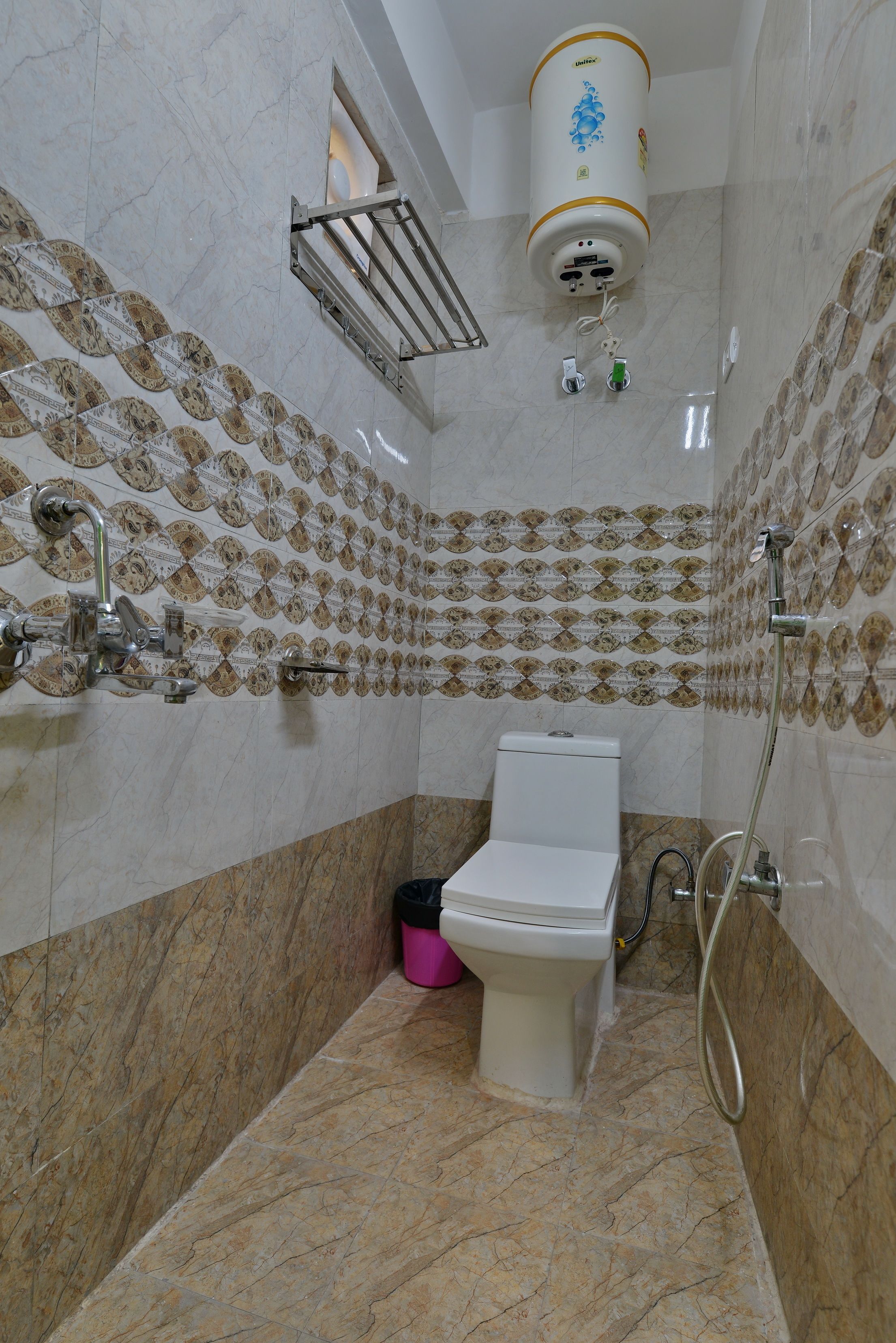 Un baño con inodoro, ducha y calentador de agua instalado en la pared.