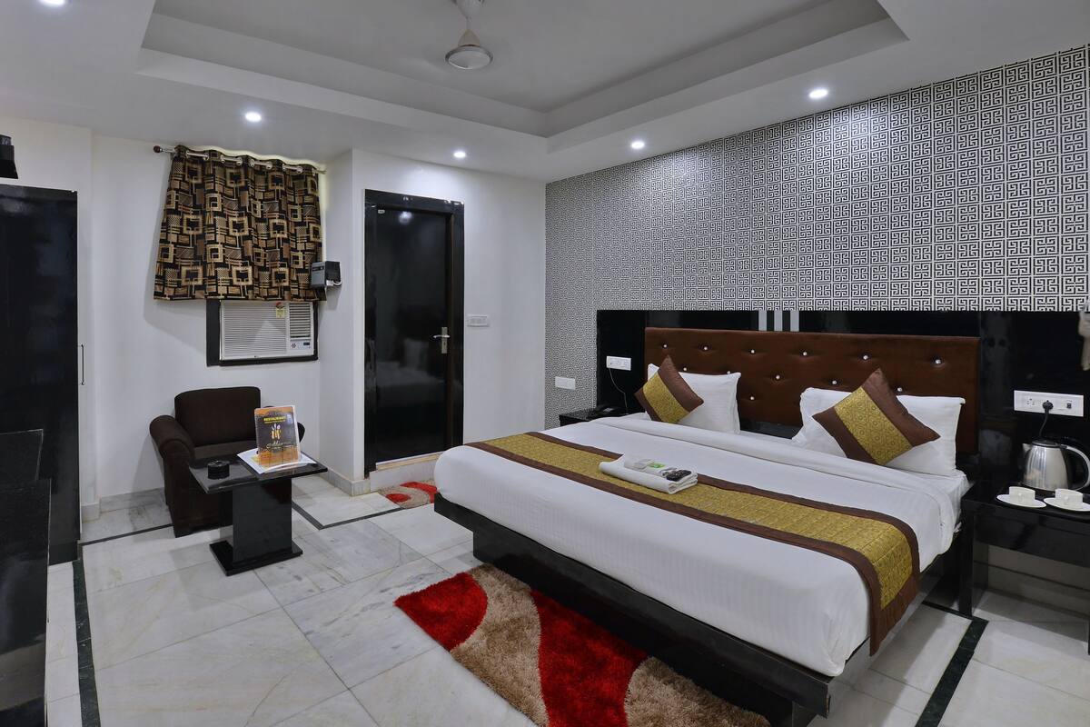 A modern hotel room with a large bed, a desk, and a chair.