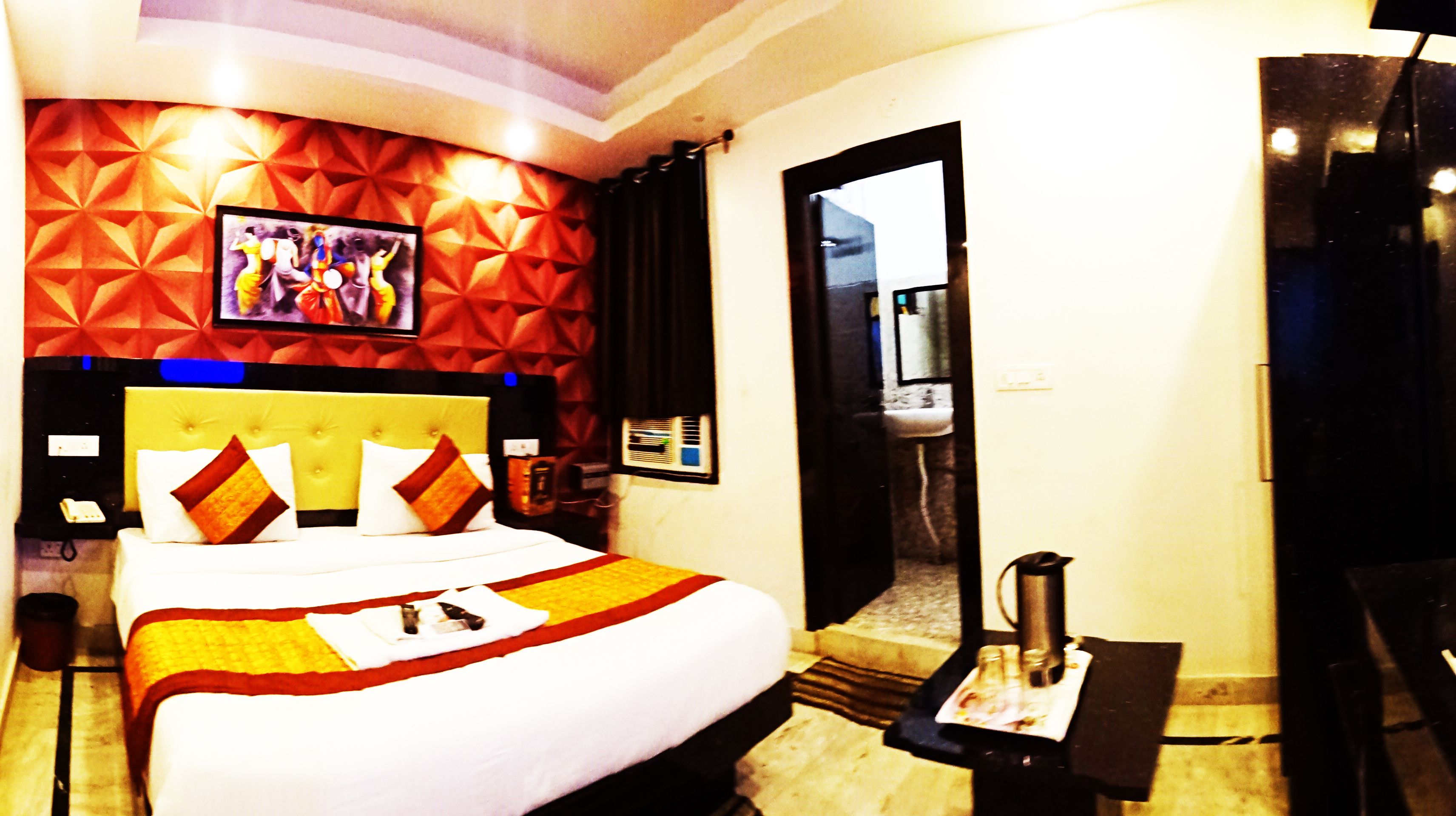 A hotel room with a large bed, a flat-screen TV mounted on the wall, and a minibar.