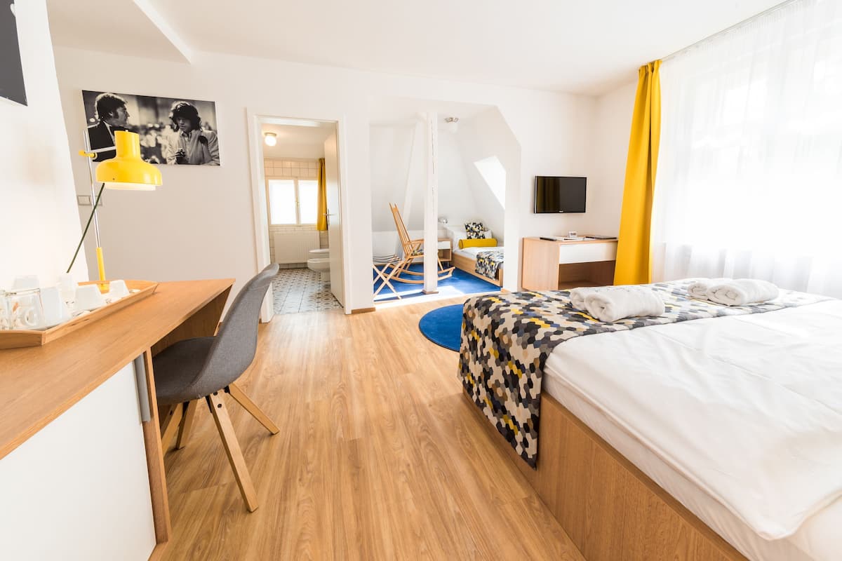 A hotel room with a bed, desk, chair, and a television.