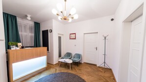 Una habitación moderna con mostrador de recepción, dos sillones, una lámpara de pie y una alfombra grande.