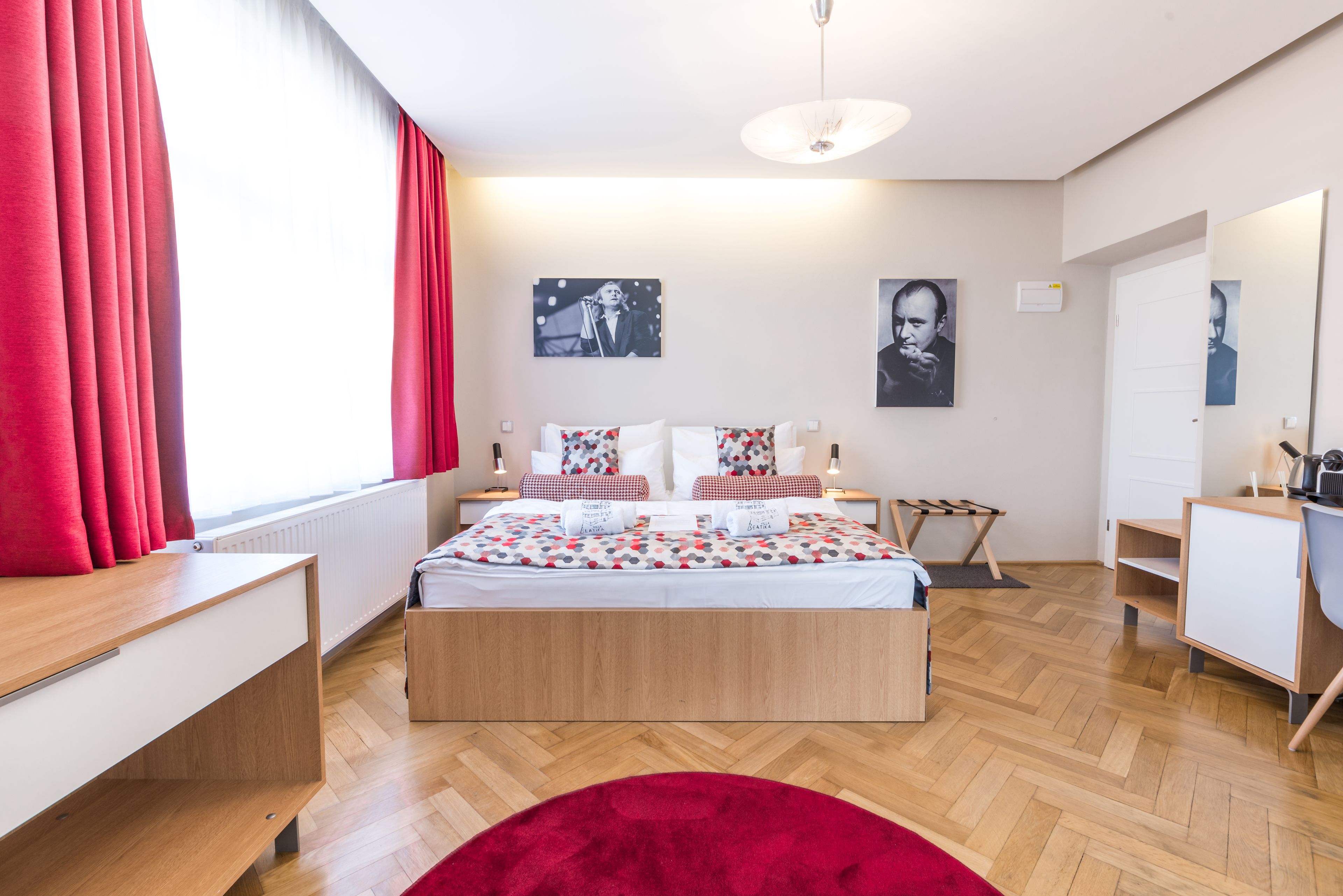 A modern bedroom with a wooden bed, red curtains, and a red rug.