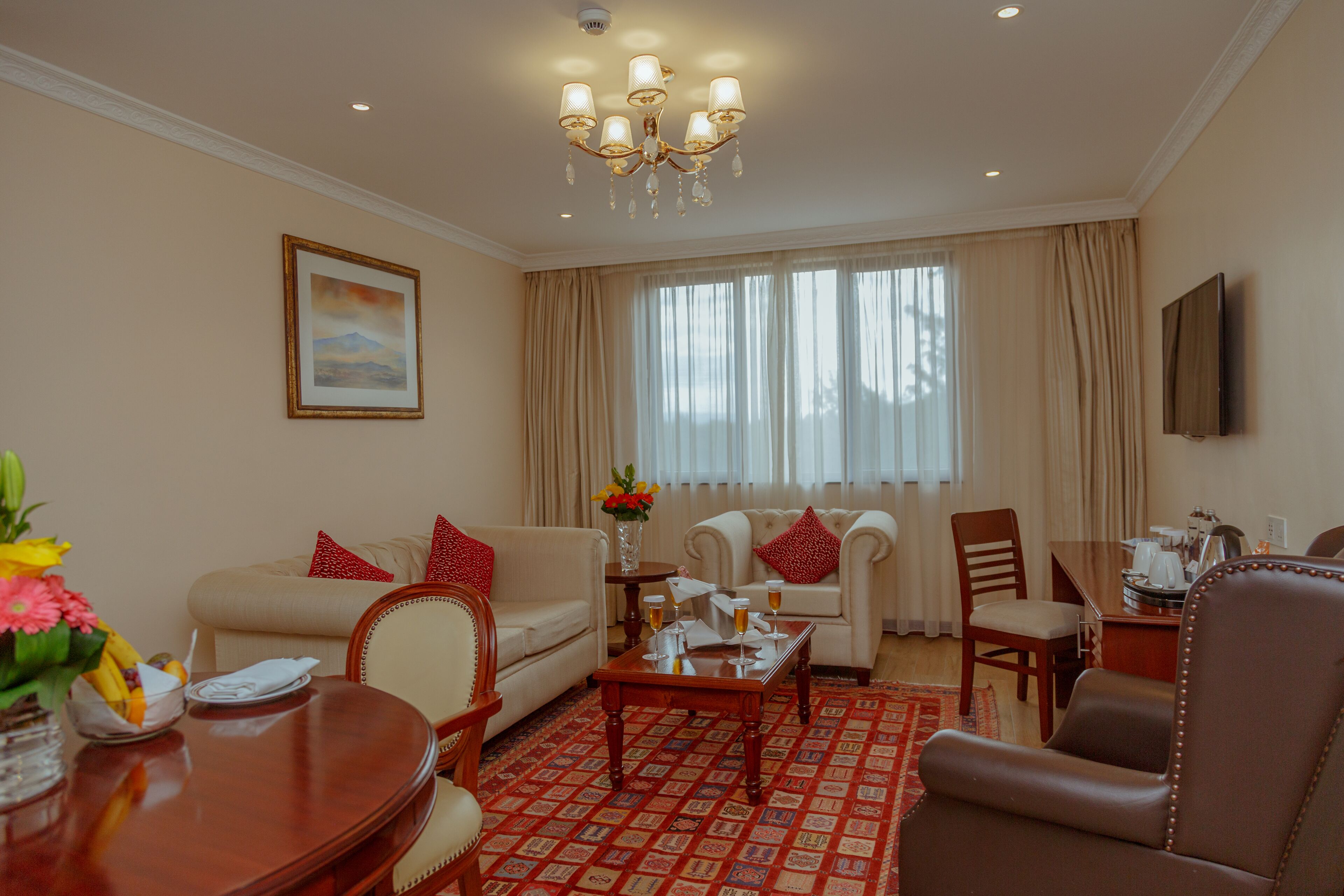 A well-lit living room with a chandelier, a sofa, a coffee table, and a dining table with chairs.