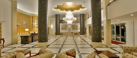 A spacious lobby with a checkered floor, a reception desk, and a chandelier.