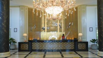 Un'ampia hall con un sontuoso lampadario, una reception e pannelli decorativi alle pareti.