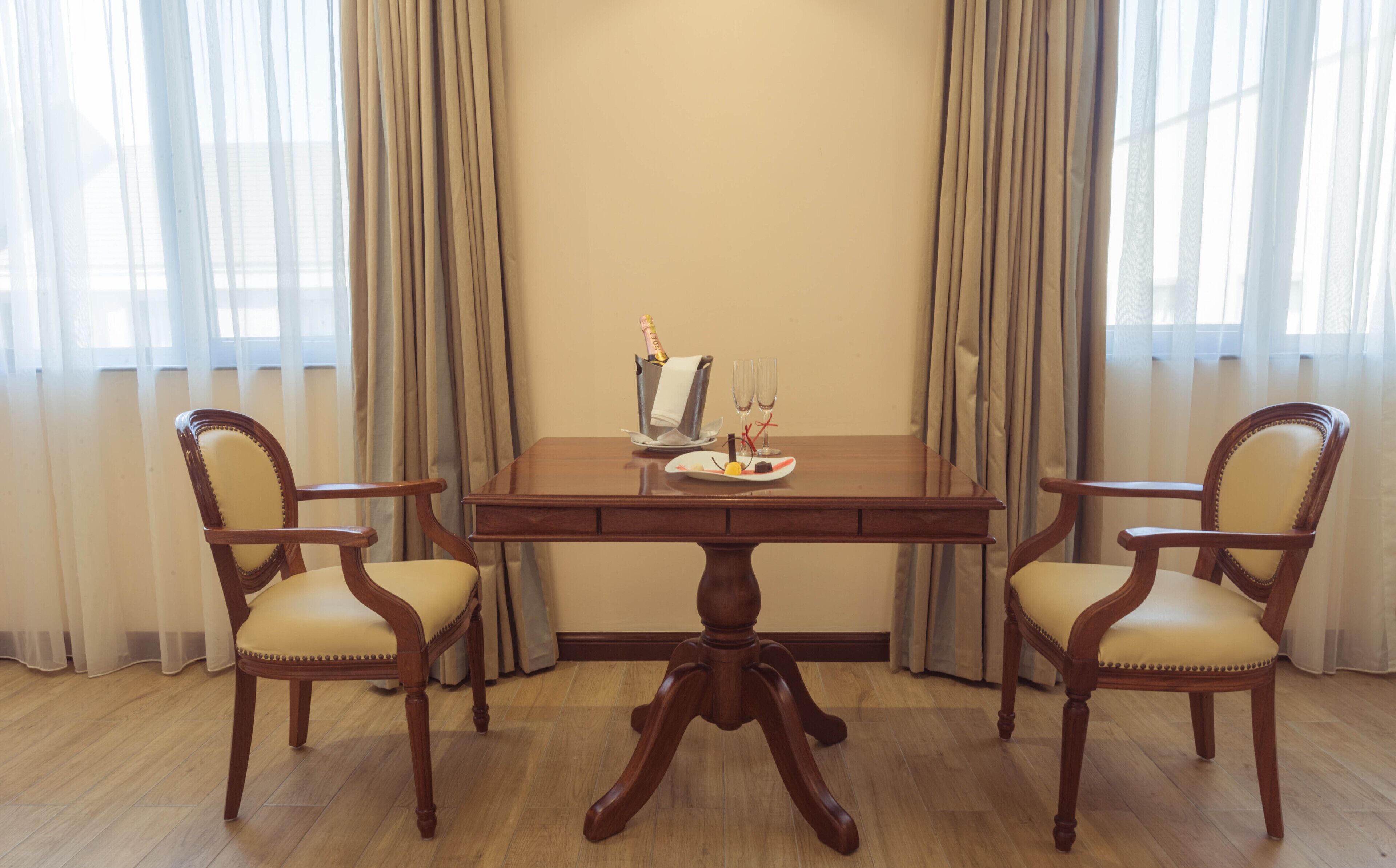 A dining table with four chairs, a bottle of champagne, and two glasses on the table.
