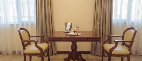 A dining table with four chairs, a bottle of champagne, and two glasses on the table.