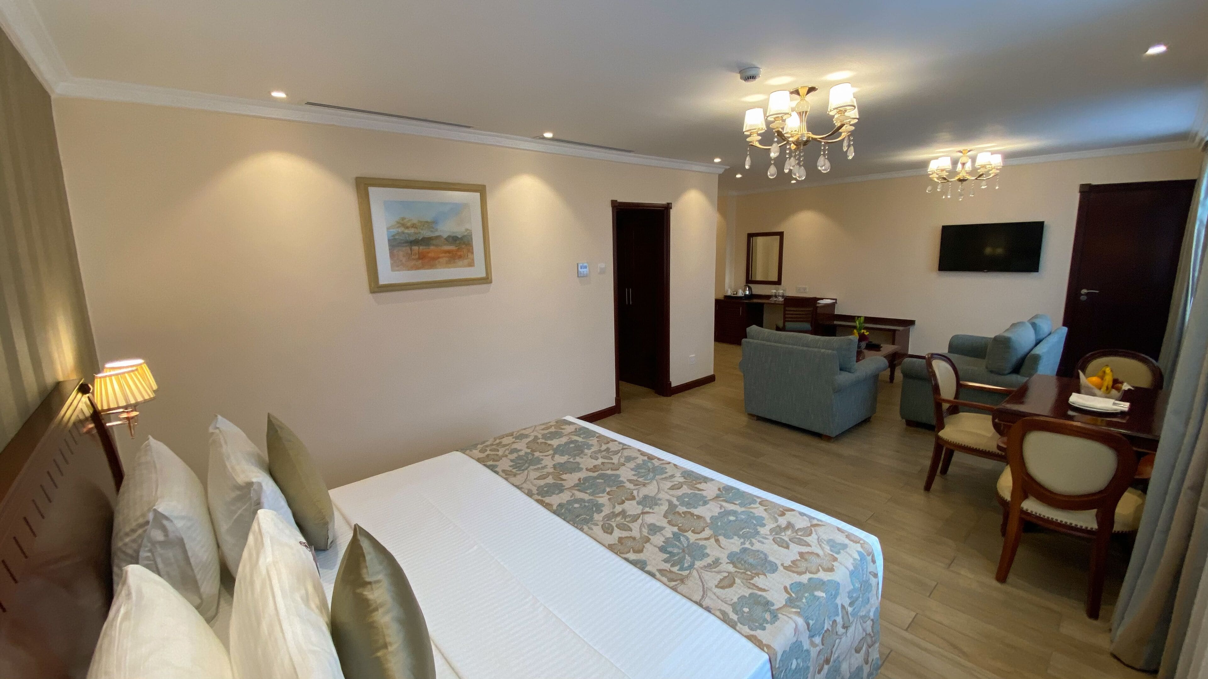 A hotel room with a bed, a sofa, a desk, and a dining table.
