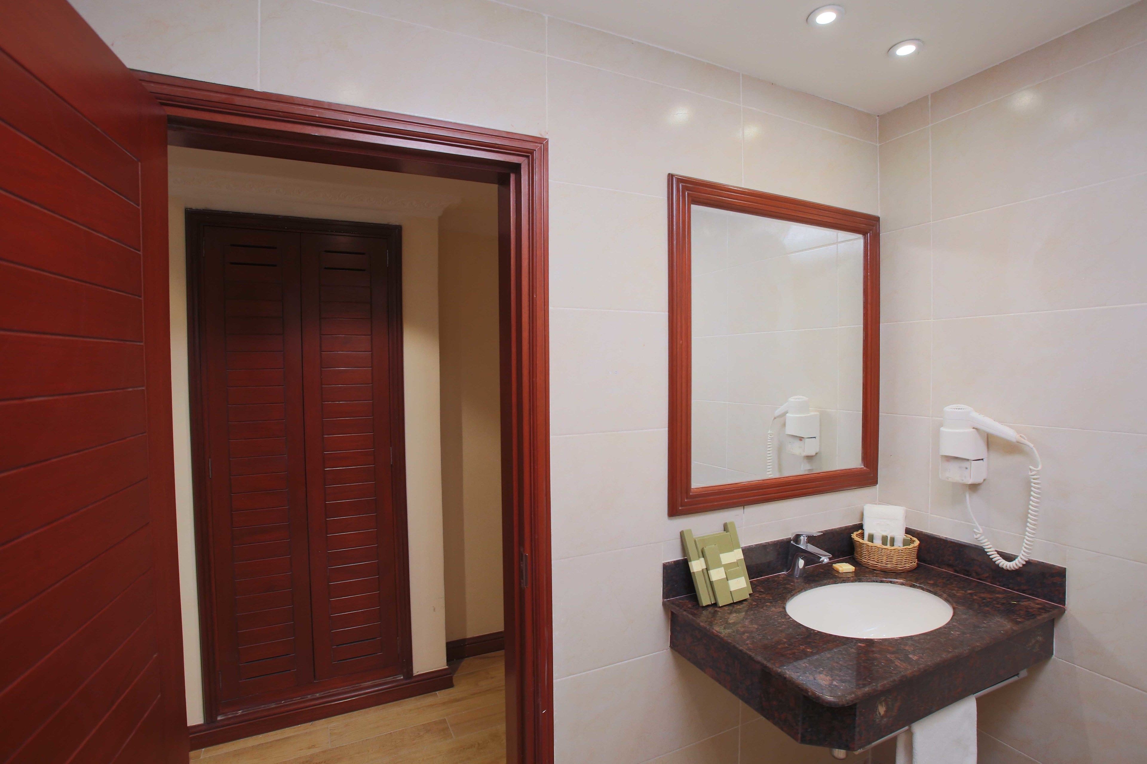 Un baño con puerta de madera, un espejo, un lavabo y un secador de pelo.