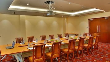 Ett konferensrum med ett långt bord, stolar, en projektor och en vattenautomat.