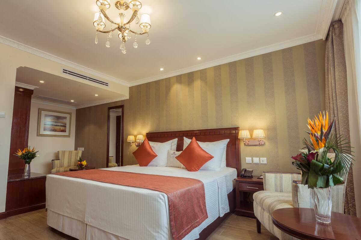 Une chambre d’hôtel avec un grand lit, un lustre, un bureau et une chaise.