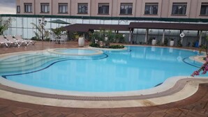 Una piscina de diseño curvo, rodeada de sillones de descanso y plantas en macetas.