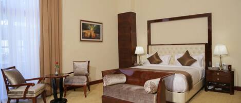 A hotel room with a large bed, two armchairs, a small table, and a nightstand.