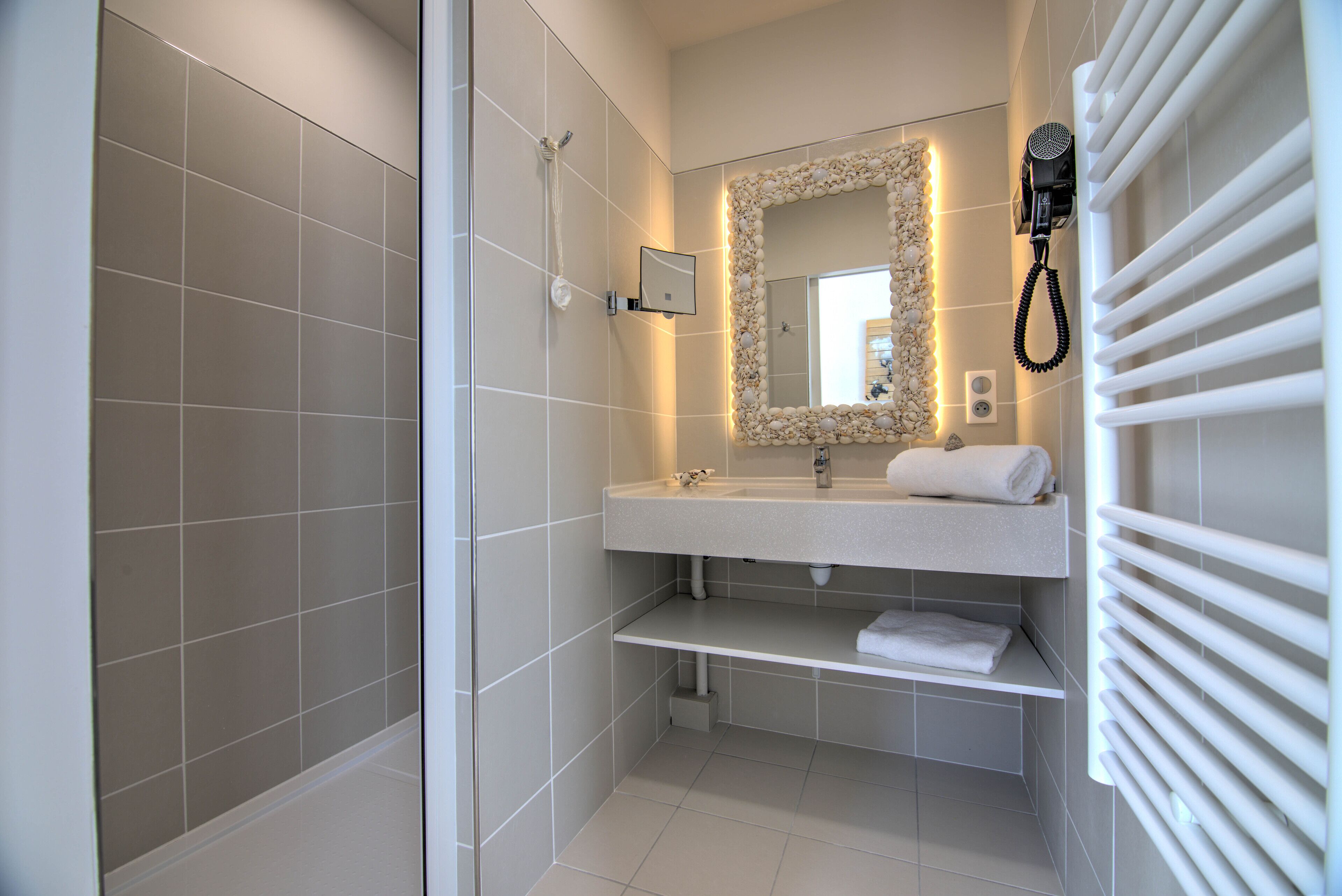A modern bathroom with a shower, a sink with a mirror, and a towel rack.