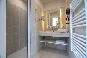 Un baño moderno con ducha, lavamanos con espejo y toallero.