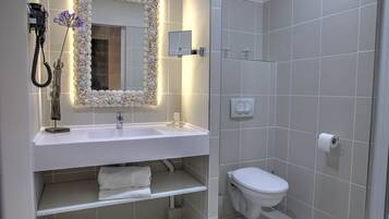 A modern bathroom with a white sink, mirror, and toilet.