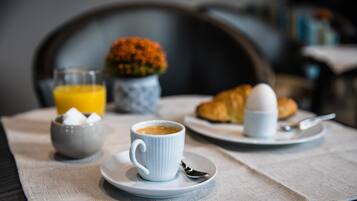Un esmorzar amb una tassa de cafè, un croissant i un got de suc d'aranja sobre una taula.