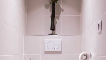 A modern bathroom with a white toilet, a hand dryer, and a toilet paper holder.