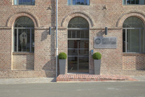 Un edificio de ladrillo con ventanas arqueadas y un letrero que dice 'HOTEL DE LA TABLETERIE'.