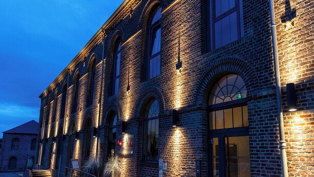 A historic building with arched windows and brick walls, illuminated by warm lighting. - Hôtel de la Tabletterie (Meru)