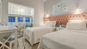 A hotel room with two beds, a desk, and a window with curtains. - Levin Otel (Cesme)